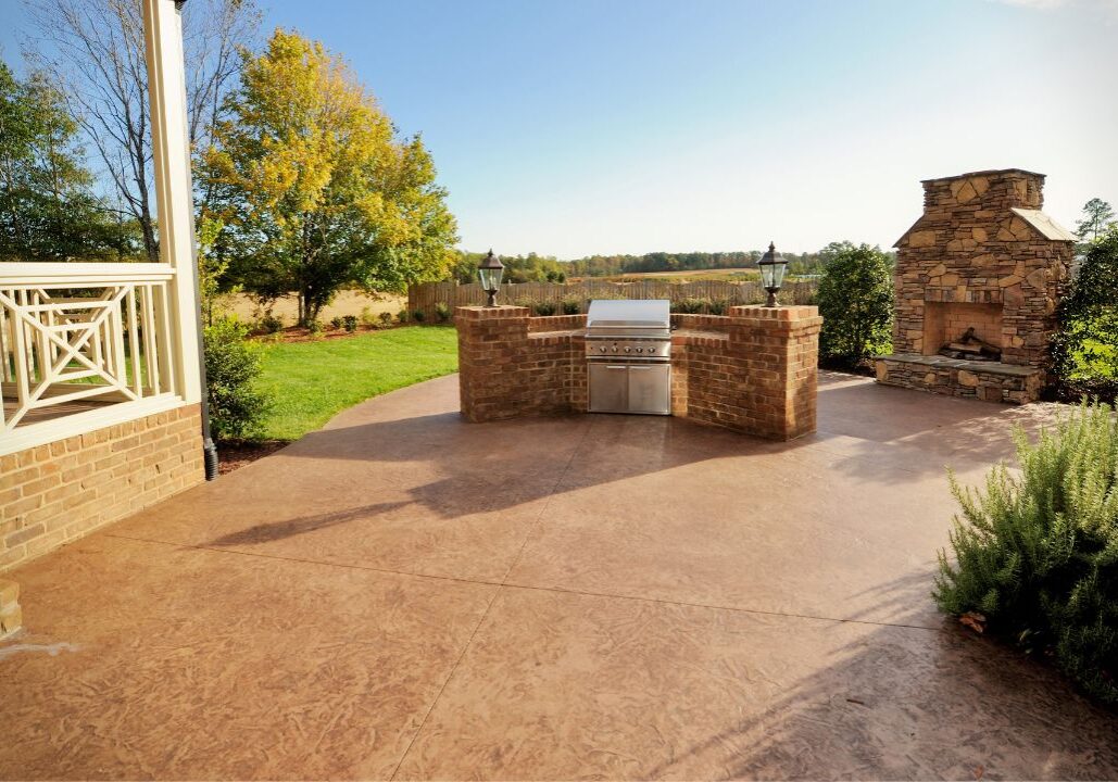 Stamped concrete patio on a sunny day with outdoor kitchen and fireplace